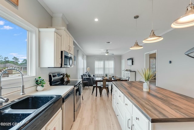 kitchen with stainless steel appliances, butcher block counters, ceiling fan, and white cabinets