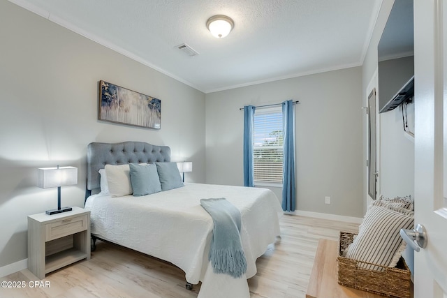 bedroom with light wood-type flooring, ornamental molding, and a textured ceiling