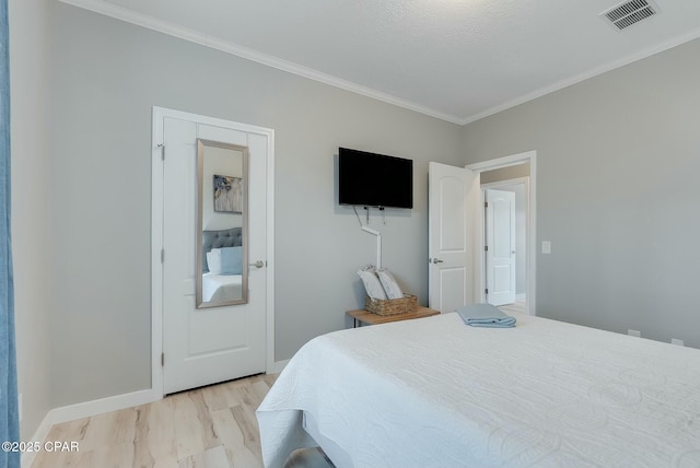 bedroom featuring a textured ceiling, light wood-type flooring, and crown molding