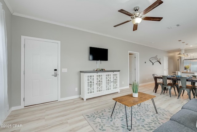 living room featuring ceiling fan, crown molding, and light hardwood / wood-style flooring