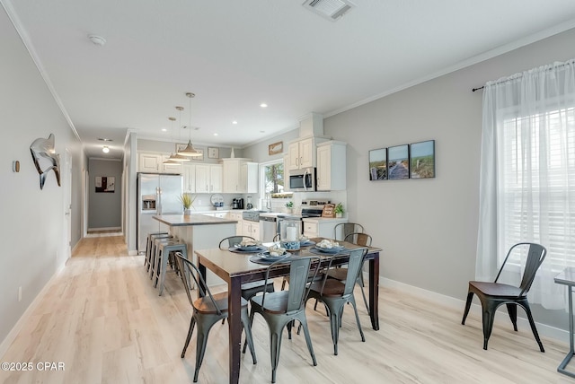 dining space with light hardwood / wood-style floors and crown molding