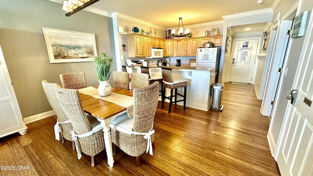 dining area with a textured ceiling, ornamental molding, a chandelier, and hardwood / wood-style flooring