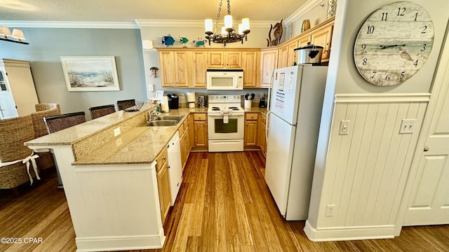 kitchen with pendant lighting, sink, crown molding, white appliances, and a kitchen breakfast bar