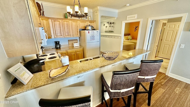 kitchen featuring light stone countertops, pendant lighting, white appliances, kitchen peninsula, and a breakfast bar