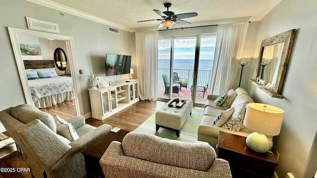 living room featuring ceiling fan, crown molding, a textured ceiling, and hardwood / wood-style flooring