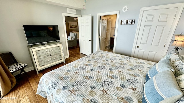 bedroom featuring a closet, dark hardwood / wood-style flooring, and ensuite bath