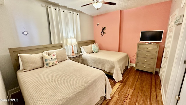 bedroom featuring ceiling fan, hardwood / wood-style floors, and a textured ceiling