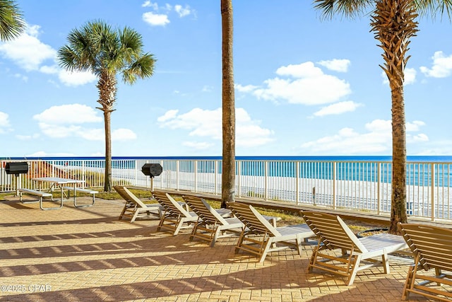 view of patio / terrace with a water view and a beach view