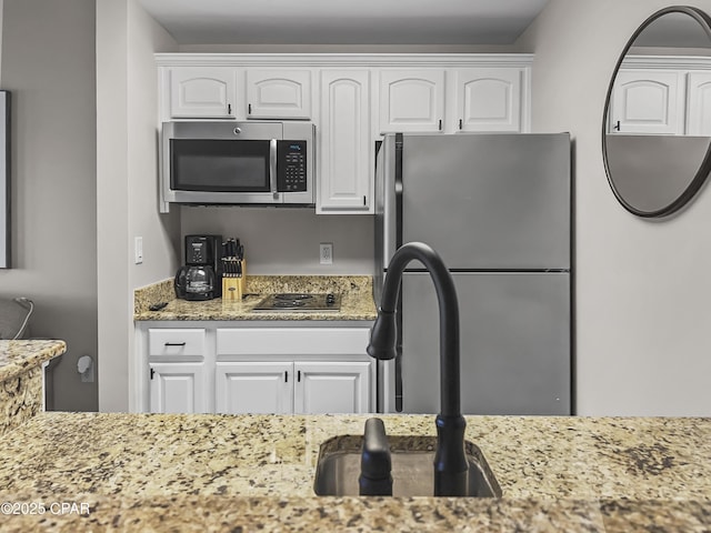 kitchen featuring white cabinetry, sink, light stone countertops, and appliances with stainless steel finishes