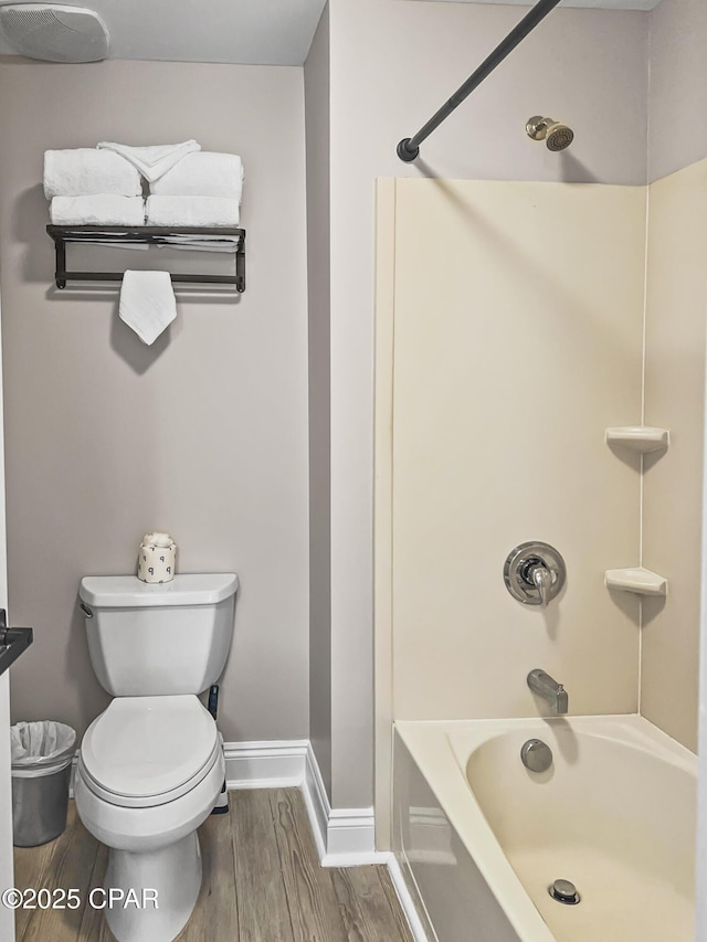 bathroom featuring hardwood / wood-style flooring, shower / washtub combination, and toilet