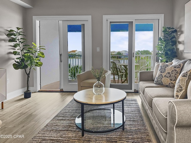 living room featuring a water view, a healthy amount of sunlight, and hardwood / wood-style floors