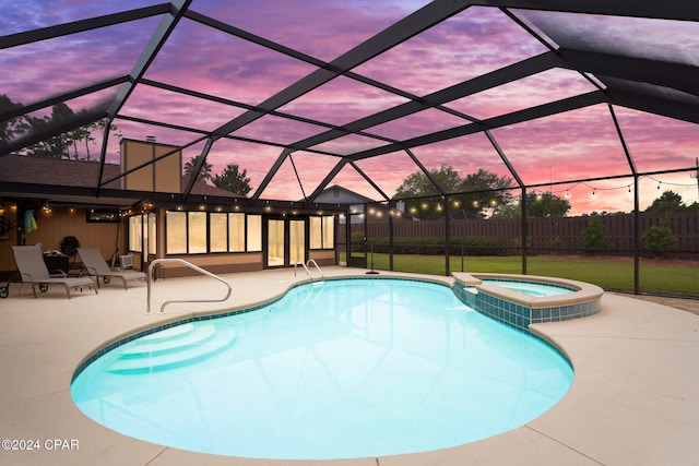 pool at dusk with a lanai, an in ground hot tub, and a patio area