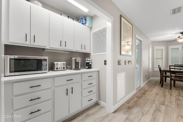 kitchen with white cabinets, ceiling fan, and light hardwood / wood-style flooring