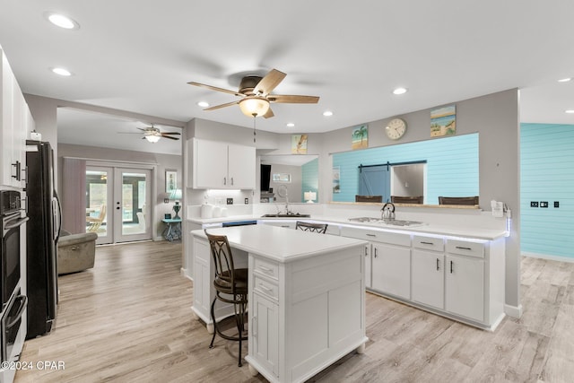 kitchen with kitchen peninsula, french doors, a breakfast bar, and white cabinetry