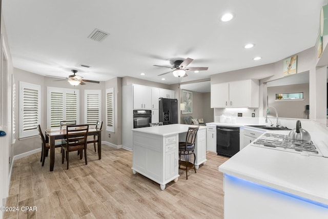 kitchen with black appliances, white cabinets, a center island, and sink