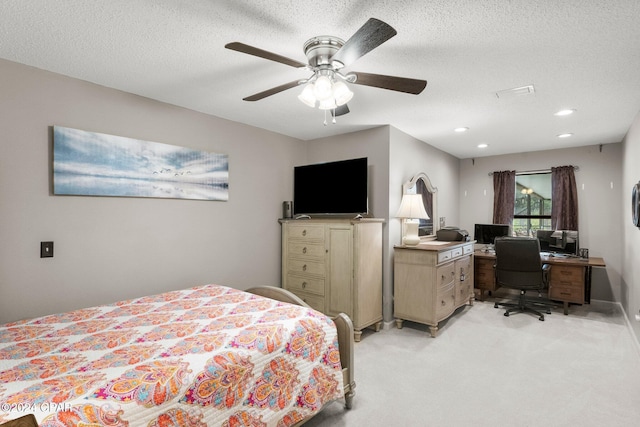 bedroom with ceiling fan, light colored carpet, and a textured ceiling