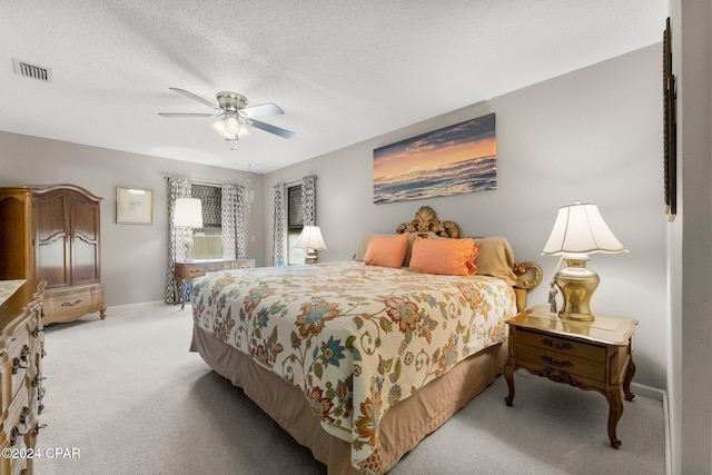 bedroom with light colored carpet, ceiling fan, and a textured ceiling