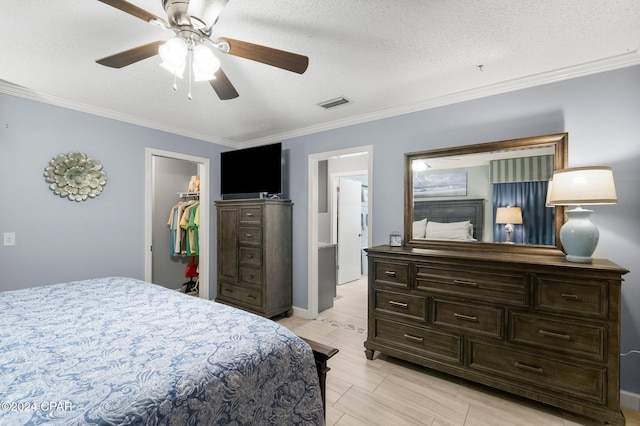 bedroom with a closet, crown molding, ceiling fan, a textured ceiling, and a walk in closet