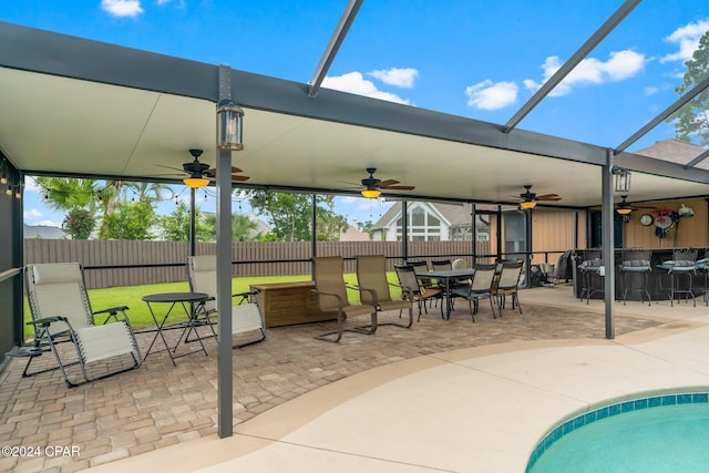 view of patio featuring a lanai, a bar, and ceiling fan