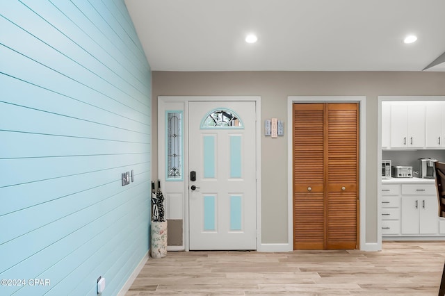 foyer with wood walls and light hardwood / wood-style flooring