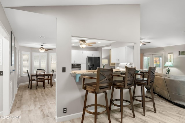 kitchen featuring white cabinets, a wealth of natural light, black appliances, and kitchen peninsula