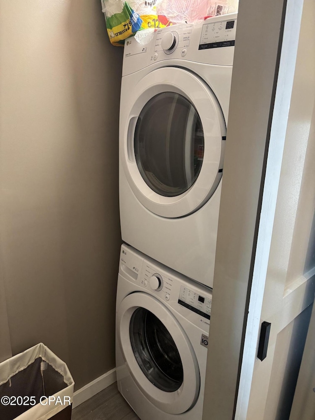 laundry room featuring dark hardwood / wood-style flooring and stacked washer / drying machine