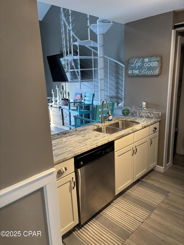 kitchen with dishwasher, dark wood-type flooring, light stone counters, white cabinets, and sink