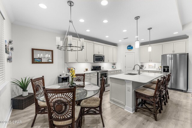 kitchen with appliances with stainless steel finishes, light wood-type flooring, decorative light fixtures, and sink