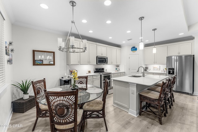 kitchen with stainless steel appliances, pendant lighting, light countertops, and a sink