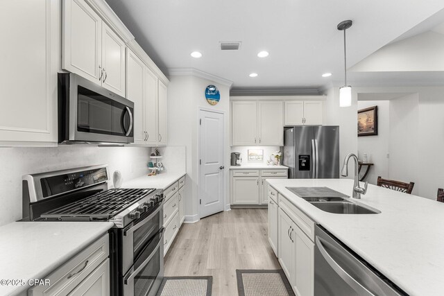 kitchen featuring stainless steel appliances, sink, white cabinetry, light hardwood / wood-style floors, and hanging light fixtures