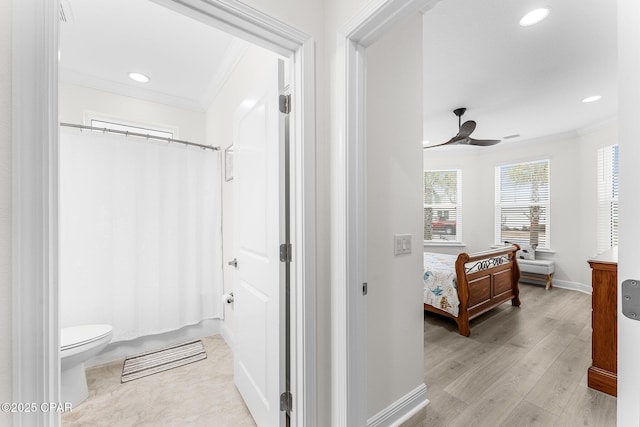 ensuite bathroom featuring ceiling fan, curtained shower, toilet, wood finished floors, and ornamental molding