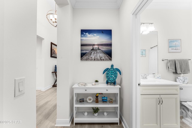 bathroom with vanity, a chandelier, hardwood / wood-style floors, and crown molding