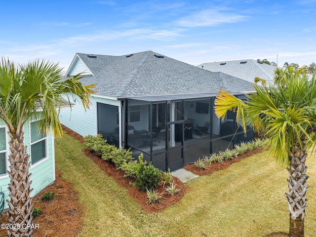 exterior space with a sunroom, a shingled roof, and a lawn