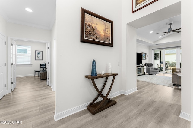 corridor featuring light wood-type flooring, crown molding, and lofted ceiling