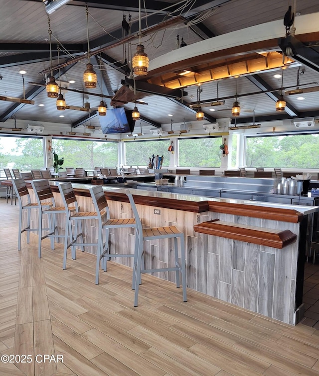 kitchen featuring light hardwood / wood-style floors, a kitchen breakfast bar, lofted ceiling with beams, and a wealth of natural light