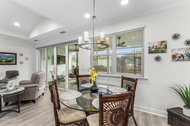 dining room featuring lofted ceiling, a chandelier, light wood-type flooring, and crown molding