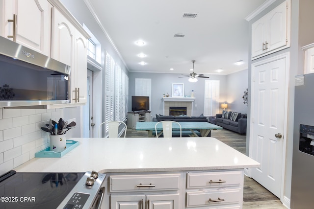 kitchen featuring white cabinets, a tile fireplace, open floor plan, light countertops, and exhaust hood