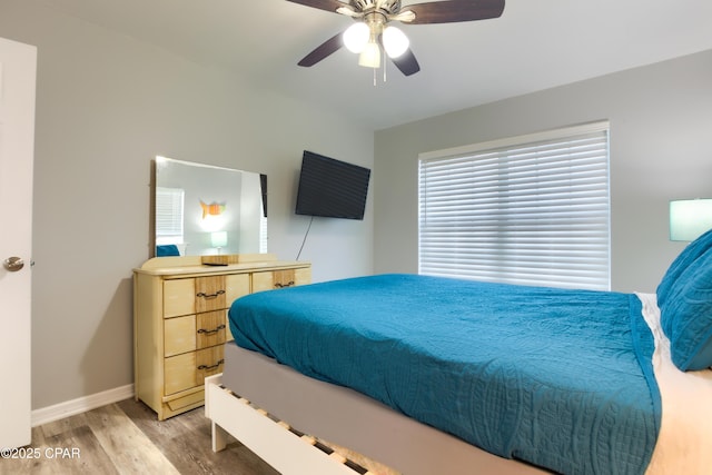 bedroom with light wood-type flooring, ceiling fan, and baseboards