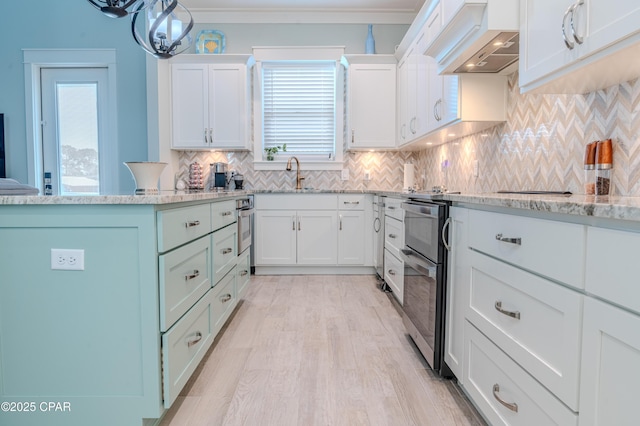 kitchen featuring pendant lighting, tasteful backsplash, sink, white cabinets, and light stone countertops