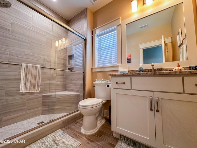 bathroom with vanity, a shower with shower door, and toilet