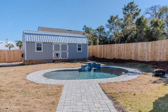 view of pool with pool water feature, a storage shed, and a lawn