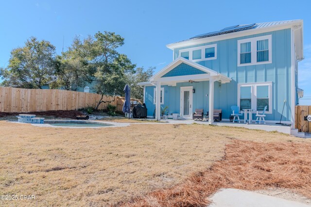 back of house with french doors, a patio, a lawn, and solar panels