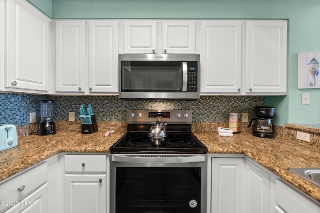 kitchen with white cabinets, decorative backsplash, and appliances with stainless steel finishes