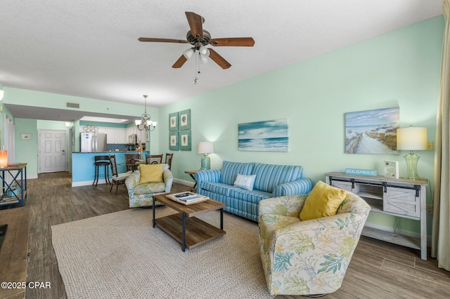 living room featuring wood-type flooring and ceiling fan with notable chandelier