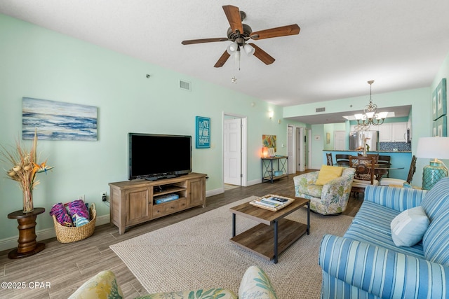 living room featuring ceiling fan with notable chandelier and light hardwood / wood-style floors