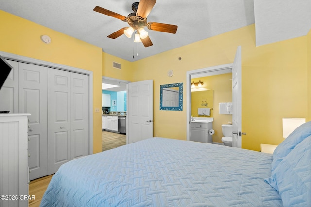 bedroom featuring ceiling fan, a closet, ensuite bath, and light wood-type flooring