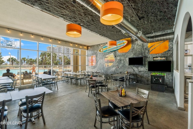 dining area featuring a water view, a towering ceiling, and concrete floors