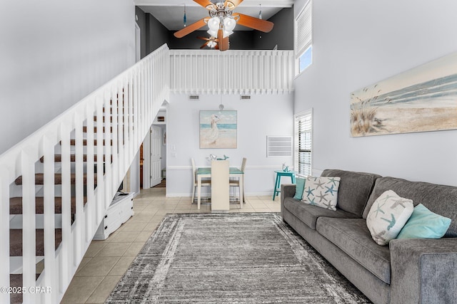 tiled living room featuring ceiling fan and a high ceiling