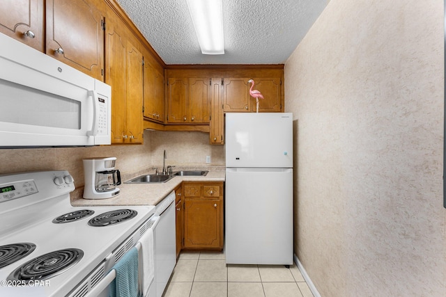 kitchen featuring sink, white appliances, a textured ceiling, and light tile patterned flooring