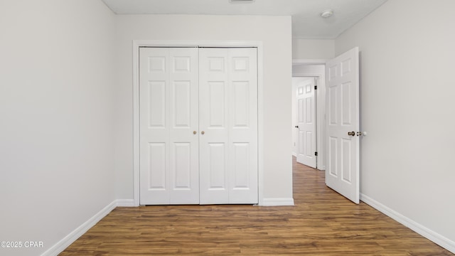 unfurnished bedroom featuring dark hardwood / wood-style flooring and a closet